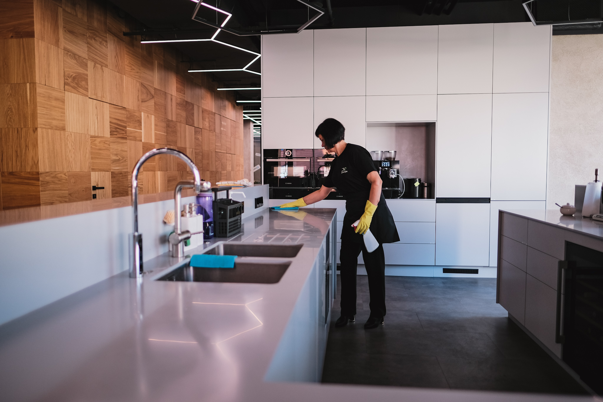 Pracovnice společnosti PF Komplet umývá pracovní plochu v kuchyni, která je součástí komerčních prostorů.